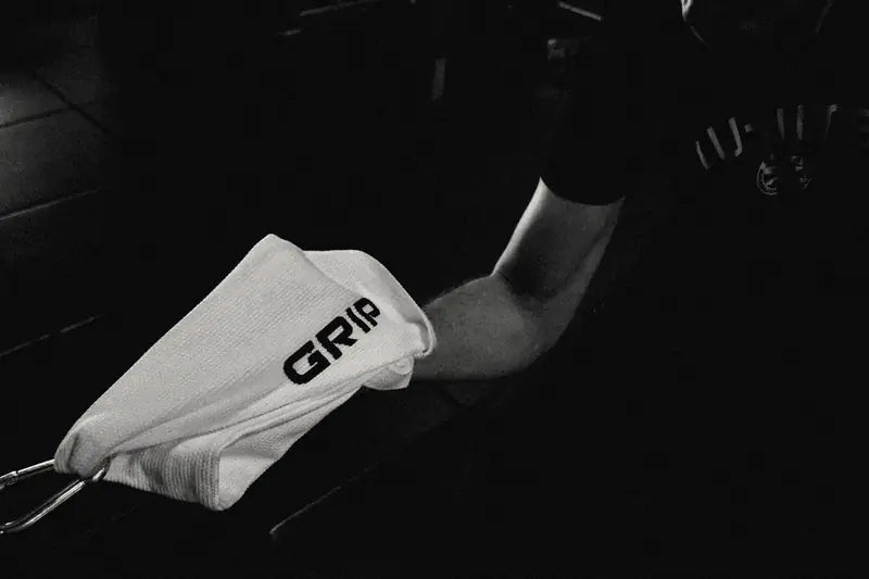 Hand gripping the GRIP tail of a Kimono Grip on a cable bar